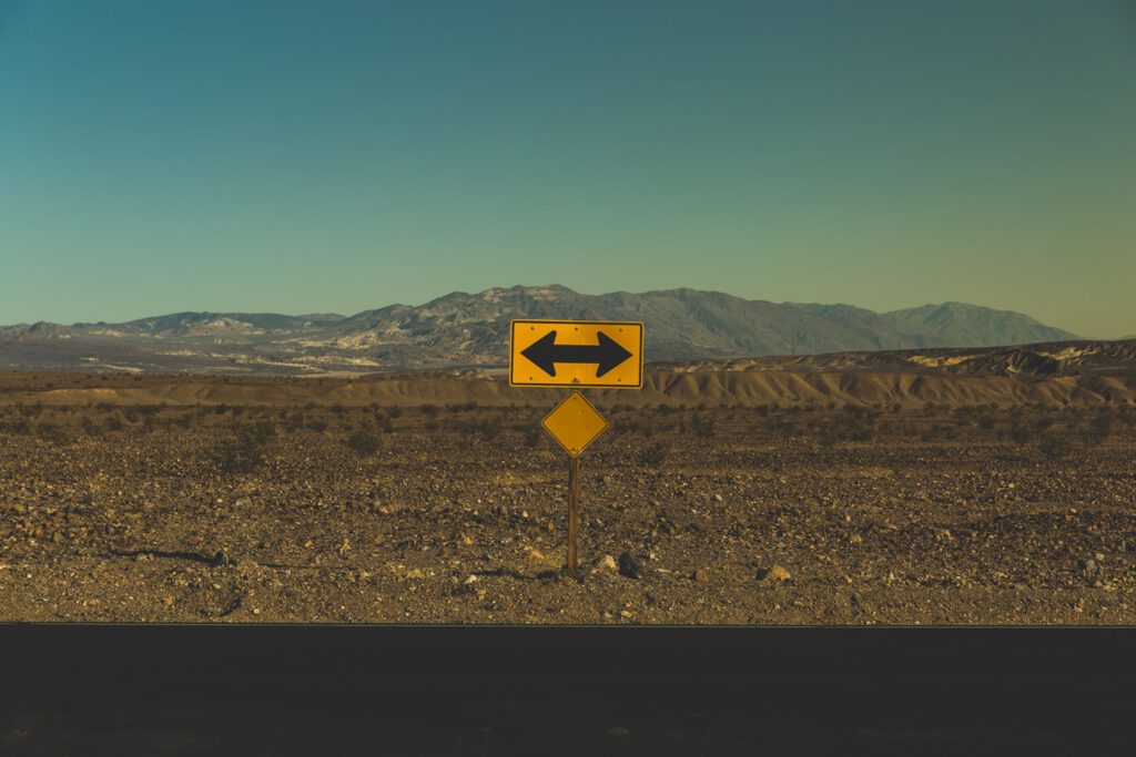A sign near in a fork in the road.