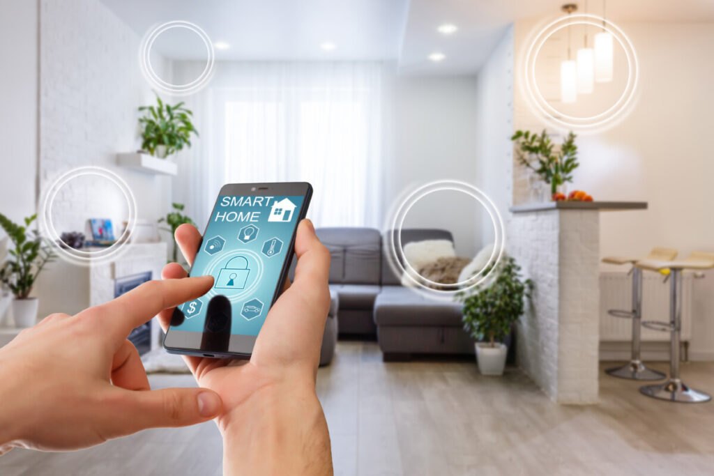 Smart home technology interface on smartphone app screen with augmented reality (AR) view of internet of things (IOT) connected objects in the apartment interior, person holding device